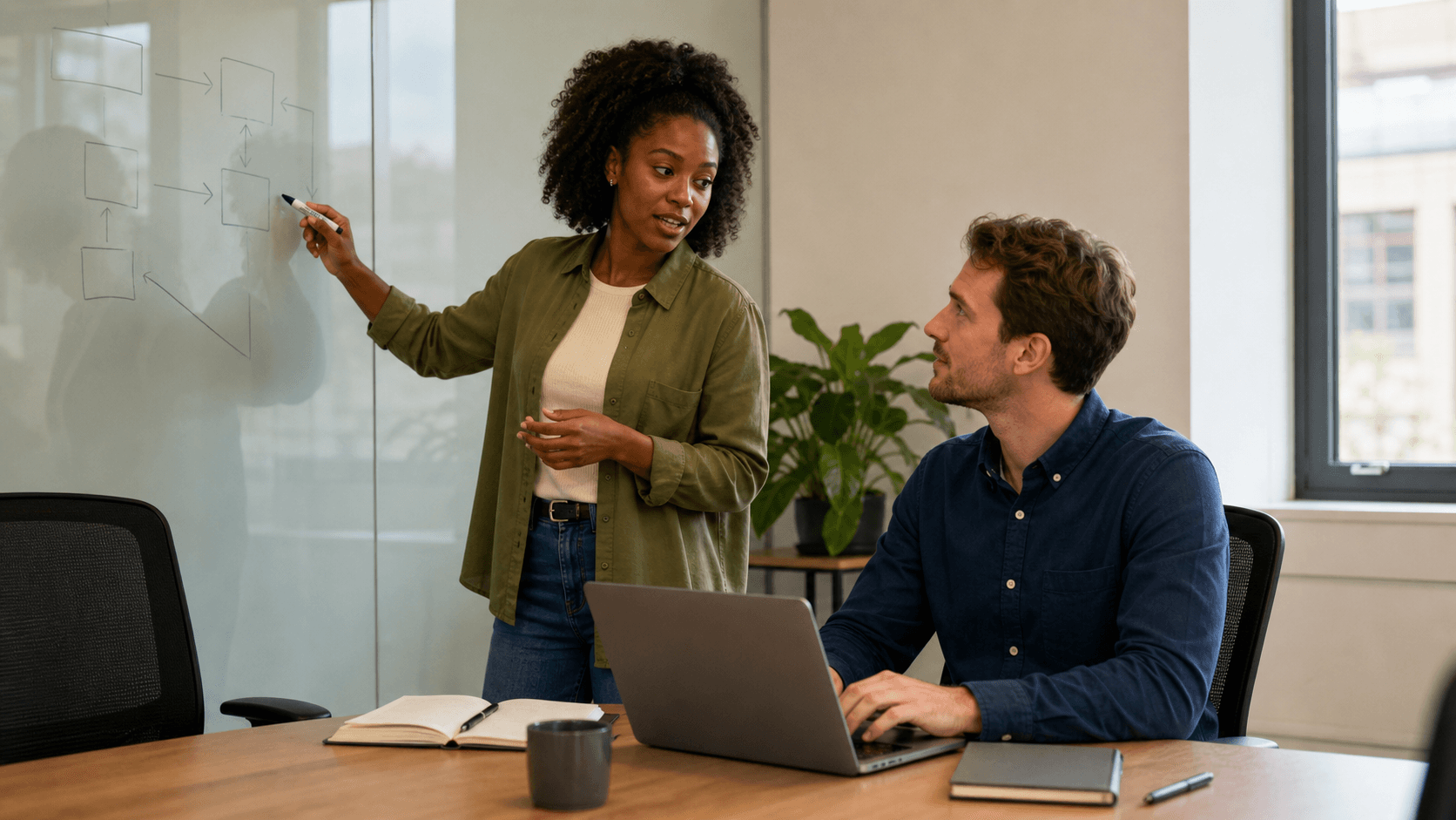 A functional consultant explains a process on a glass board while an Odoo developer works at a laptop